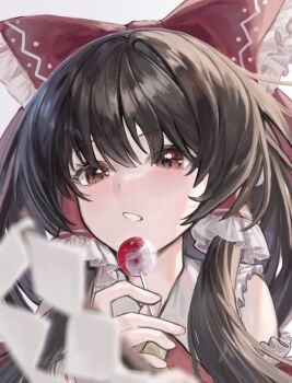  1girl ao_hoshi ascot bare_shoulders black_hair bow brown_eyes candy collared_shirt commentary_request detached_sleeves dot_nose food frilled_bow frilled_hair_tubes frilled_shirt frilled_sleeves frills gohei hair_between_eyes hair_bow hair_over_eyes hair_tubes hakurei_reimu highres holding holding_candy holding_food holding_lollipop lollipop long_hair long_sidelocks looking_down portrait red_bow red_shirt shide shirt sidelocks simple_background solo touhou white_background yellow_ascot yin_yang 