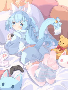 1girl absurdres animal_ear_fluff animal_ears bell blue_eyes blue_hair blue_hoodie blue_shorts blue_tail bow cat_ears cat_girl cat_tail controller frilled_shorts frills game_controller hair_ornament handheld_game_console highres hood hoodie leg_warmers long_hair looking_at_viewer lying on_stomach original paw_print pillow shorts soles solo stuffed_animal stuffed_toy tail tail_bell tail_ornament teddy_bear thighhighs two_side_up