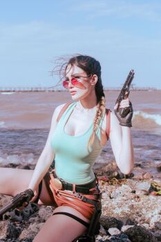 1girl argentine_(nationality) bare_arms black_gloves braid braided_ponytail breasts cleavage cosplay day fingerless_gloves gloves gun handgun highres holding holding_gun holding_weapon lara_croft lara_croft_(cosplay) lips medium_breasts real_life shirt short_shorts shorts single_braid sitting sophie_valentine sunglasses sunlight tomb_raider water weapon wide_hips