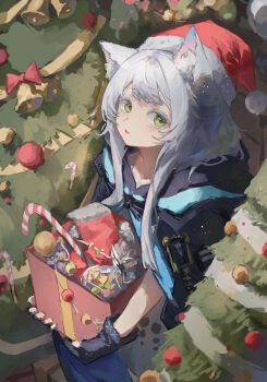 1girl absurdres animal_ear_fluff animal_ears arknights bell black_gloves black_jacket blush bow candy candy_cane christmas christmas_tree commentary english_commentary fingerless_gloves food fur-trimmed_headwear fur_trim gloves green_eyes grey_hair hat highres holding hood hood_down hooded_jacket infection_monitor_(arknights) jacket light_particles long_hair looking_at_viewer mumu_millhayes parted_lips red_bow red_hat rosmontis_(arknights) santa_hat solo