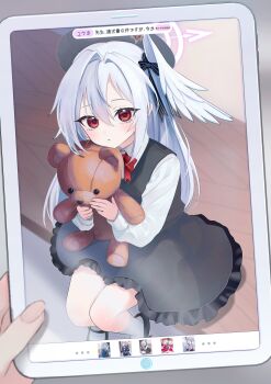 1girl :< absurdres aged_down alternate_costume beret black_dress black_hat black_ribbon black_shoes blue_archive blush bow bowtie cellphone_photo collared_shirt commentary_request dress frilled_dress frills hair_between_eyes halo hat head_wings highres holding holding_stuffed_toy holding_tablet_pc hugging_doll hugging_object long_hair long_sleeves looking_at_viewer mary_janes pinafore_dress pink_halo red_bow red_bowtie red_eyes ribbon shirt shoes single_head_wing sitting sleeveless sleeveless_dress socks solo stuffed_animal stuffed_toy suzumi_(blue_archive) tablet_pc tax_(zeita_gundam) teddy_bear white_hair white_shirt white_socks wings