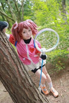 1girl absurdres asian bike_shorts bike_shorts_under_skirt brown_hair cosplay gloves green_eyes highres japanese_(nationality) legs looking_at_viewer net photo_(medium) real_life saru_getchu sayaka_(saru_getchu) skirt smile solo sony thighs tree twintails