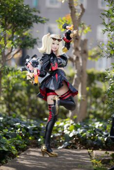 1girl 2025 absurdres arm_strap arms_up belt black_jacket black_skirt black_tube_top blonde_hair blurry building burnice_white burnice_white_(cosplay) cosplay cosplay_photo day depth_of_field dual_wielding eyewear_on_head flamethrower full_body grin high_heels highres holding jacket japanese_(nationality) leg_up looking_at_viewer navel orange-tinted_eyewear outdoors photo_(medium) red-tinted_eyewear shadow simple_background skirt sleeveless_turtleneck_shirt smile solo spiked_belt spiked_jacket standing standing_on_one_leg strapless sunglasses sunlight suuuuu3920 thigh_belt thigh_strap thighhighs tinted_eyewear tree tube_top twintails weapon white_background zenless_zone_zero zettai_ryouiki