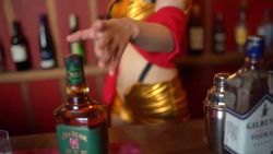 1girl alcohol animated bar_(place) blue_eyes bottle breasts brown_thighhighs cleavage commercial cosplay cowboy_bebop faye_valentine faye_valentine_(cosplay) female_focus green_eyes hairband headband japanese_(nationality) large_breasts looking_at_viewer medium_hair model photo_(medium) purple_hair real_life shibuya_kaho short_hair short_shorts shorts smile solo sound thighhighs video walking whiskey