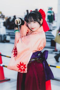 1girl absurdres black_eyes black_hair bow cosplay fighting_stance fingerless_gloves from_side gloves hair_ribbon highres japanese_(nationality) japanese_clothes long_hair long_skirt looking_at_viewer pink_lips ponytail red_bow ribbon sakura_taisen sega shinguuji_sakura skirt smile solo sword weapon