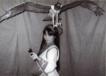 1girl ainu_clothes alternate_costume asian black_hair breasts cosplay hair_ribbon highres japanese_(nationality) long_hair looking_at_viewer mamahaha medium_breasts monochrome nakoruru photo_(medium) ribbon samurai_spirits snk the_king_of_fighters weapon