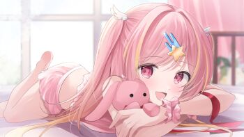 1girl :d bare_legs barefoot blonde_hair blurry blurry_background commission crop_top crossed_arms day foot_out_of_frame foot_up gradient_hair hair_intakes hair_ornament head_rest indie_virtual_youtuber indoors kurage_cc light_blush long_hair looking_at_viewer lying maygi multicolored_hair on_bed on_stomach open_mouth pink_eyes pink_hair pink_shorts pink_wrist_cuffs red_ribbon ribbon shorts skeb_commission smile solo star_(symbol) star_hair_ornament streaked_hair stuffed_animal stuffed_rabbit stuffed_toy sunlight swept_bangs two_side_up virtual_youtuber window wing_hair_ornament wrist_cuffs