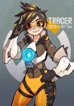 1girl black_gloves bodysuit brown_eyes brown_hair brown_jacket character_name commentary_request coogee cowboy_shot dated earrings gloves goggles grey_background jacket jewelry looking_at_viewer orange_bodysuit overwatch overwatch_(logo) salute short_hair smile solo tracer_(overwatch) two-finger_salute