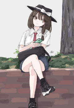 1girl asymmetrical_sidelocks bag black_bag black_hat black_shoes black_socks blue_shorts bow brown_eyes brown_hair closed_mouth collared_shirt commentary_request crossed_legs grass hair_between_eyes hair_bow hat hat_bow highres holding holding_phone kashiwada_kiiho looking_to_the_side medium_hair phone shirt shoes short_sleeves shorts sidelocks signature sitting socks solo touhou tree usami_renko white_bow white_shirt