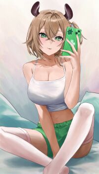 1girl animal_ears armpit_crease blush breasts bright_pupils brown_hair camisole cellphone cleavage commentary crop_top crossed_bangs double-parted_bangs fingernails foot_out_of_frame green_eyes green_shorts hair_between_eyes hair_intakes hand_up highres holding holding_phone indian_style indie_virtual_youtuber large_breasts legs_apart looking_at_object midriff navel nimi_nightmare phone pillow ravennvi short_hair shorts side_ponytail sitting smartphone solo symbol-only_commentary taking_picture tapir_ears tapir_girl thighhighs tongue tongue_out virtual_youtuber white_camisole white_pupils white_thighhighs