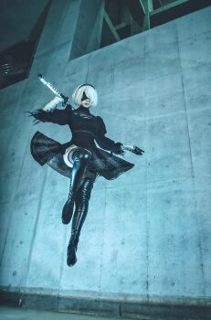 2b_(nier:automata) absurdres black_boots black_dress black_hairband blindfold boots cosplay_photo dress gloves hairband high_heel_boots high_heels highres holding holding_sword holding_weapon juliet_sleeves jumping katana long_sleeves midair nier:automata nier_(series) photo_(medium) puffy_sleeves puutin_cos short_hair side_slit sword thigh_boots virtuous_contract weapon white_hair