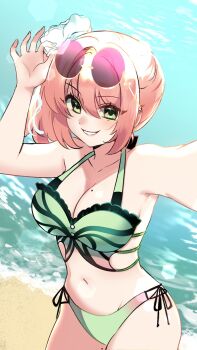 1girl arm_up beach bikini breasts cleavage collarbone commentary cowboy_shot day english_commentary eyewear_on_head flower green_bikini green_eyes hair_between_eyes hair_flower hair_ornament highres large_breasts looking_at_viewer mole mole_on_breast navel ocean original outdoors parted_lips pink_hair purple-tinted_eyewear round_eyewear ryuuxin selfie short_hair side-tie_bikini_bottom smile solo stomach sunglasses swimsuit tinted_eyewear water white_flower