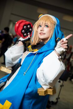 1boy 2024 absurdres androgyne_symbol androgynous aqua_eyes arc_system_works asian black_skirt blonde_hair blue_shoes blurry blurry_background blush brand_name_imitation bridget_(guilty_gear) bridget_(guilty_gear)_(cosplay) chain commentary cosplay cosplay_photo cross cuffs depth_of_field dutch_angle fingerless_gloves full_body gloves green_eyes grin guilty_gear guilty_gear_strive habit handcuffs highres holding holding_weapon hood hood_up hoodie indoors jacket japanese_(nationality) lips lipstick long_sleeves looking_at_viewer makeup male_focus medium_hair miniskirt one_eye_closed open_clothes open_hoodie photo_(medium) pleated_skirt puffy_long_sleeves puffy_sleeves real_life shadow shoes skirt smile socks solo solo_focus spread_fingers standing standing_on_one_leg teeth trap turtleneck upper_teeth_only walking weapon wink yo-yo yunomi_ochawan