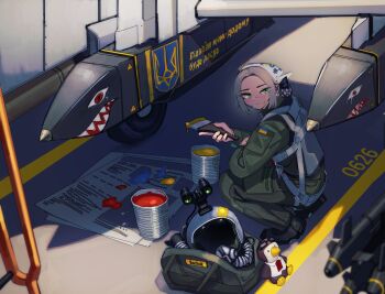 1girl absurdres air-to-air_missile aircraft bag bendit blonde_hair blue_paint commission earrings embroidery expressionless flight_suit floral_print freckles from_above from_side g-suit goggles golden_eagle green_jumpsuit hair_scarf helmet highres holding holding_brush holding_paintbrush hoop_earrings jewelry jumpsuit looking_at_viewer looking_back military military_patch military_uniform military_vehicle name_tag newspaper night_vision_device nose_art olena_bozhuk original outdoors oxygen_mask paint paint_can paint_splatter paint_splatter_on_face paint_stains paintbrush painting_(action) parted_bangs pilot_helmet red_eyes red_paint rocket russo-ukrainian_war sharp_teeth shoulder_bag sign soldier squatting stuffed_animal stuffed_toy su-24 teeth translated trim_brush tryzub ukraine ukrainian_air_force ukrainian_flag ukrainian_text vehicle_focus warning_sign