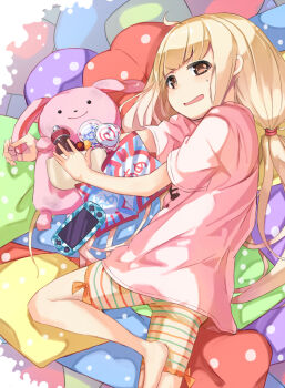 1girl barefoot blonde_hair brown_eyes candy commentary_request food foot_out_of_frame futaba_anzu handheld_game_console idolmaster idolmaster_cinderella_girls kuresuku_(lessons) lollipop long_hair pennant pillow pink_shirt shirt short_sleeves shorts striped_clothes striped_shorts stuffed_animal stuffed_rabbit stuffed_toy swirl_lollipop