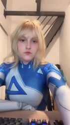 1girl animated arms_up ass blonde_hair blue_bodysuit bodysuit brazilian_(nationality) breasts cosplay curvy fantastic_four hat highres indoors long_hair looking_at_viewer marvel marvel_rivals memepantazis multicolored_bodysuit photo_(medium) real_life sitting smile sound stretching sue_storm sue_storm_(cosplay) tagme two-tone_bodysuit video white_background