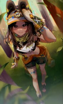 1girl animal_ears animification bandana bandana_around_neck bent_over blurry blurry_foreground brown_hair brown_shoes brown_shorts chinchilla_ears chinchilla_girl commentary cosplay crop_top day english_commentary fur-lined_gloves fur-trimmed_mittens fur_trim genshin_impact gloves grass green_eyes hand_on_another&#039;s_head hand_up kachina_(genshin_impact) kachina_(genshin_impact)_(cosplay) kanako_(fuwachu) kemonomimi_mode kristen_mcguire leaf long_hair mittens navel orange_mittens orange_visor outdoors plant real_life shirt shoes shorts sidelocks smile sparkle stomach tree visor_cap voice_actor voice_actor_connection