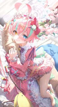 1girl absurdres bell blue_archive blue_eyes blurry blush bow bowtie dress frilled_dress frills hair_ornament hairclip heterochromia highres hoshino_(blue_archive) hugging_object jingle_bell long_sleeves looking_at_viewer lying multicolored_hair nagomi_naka nail_polish on_side pillow pillow_hug pink_dress pink_hair purple_bow purple_bowtie red_nails smile solo virtual_youtuber yellow_eyes