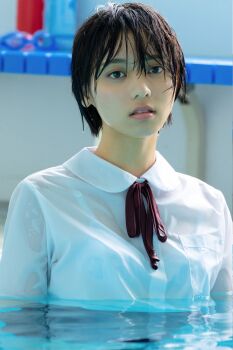 1girl black_hair blurry blurry_background flat_chest highres indoors japanese_(nationality) looking_at_viewer monami_suzu partially_submerged photo_(medium) pool poolside school_uniform short_hair standing water wet wet_clothes