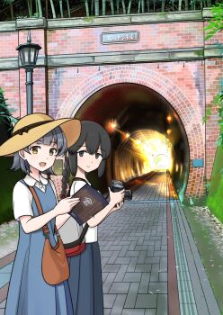 2girls arare_(kancolle) arare_(maizuru)_(kancolle) bag bamboo black_eyes black_hair blue_dress book braid brown_hat camera closed_mouth commentary_request day dress grey_hair hat highres hitakikan holding holding_book holding_camera isonami_(autumn_mode)_(kancolle) isonami_(kancolle) isonami_(photographer)_(kancolle) kantai_collection lamppost long_hair looking_at_viewer multiple_girls open_mouth outdoors shirt short_hair short_sleeves single_braid skirt sun_hat tunnel white_shirt