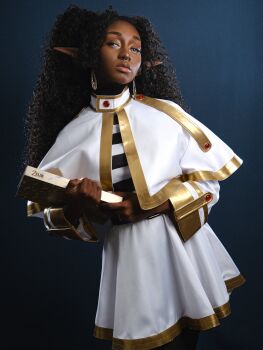 1girl black_hair blue_eyes book capelet cosplay curly_hair dark-skinned_female dark_skin earrings elf fingernails frieren highres jahara_jayde jewelry long_fingernails long_hair long_pointy_ears nail_polish pointy_ears real_life septum_piercing skirt sousou_no_frieren striped_clothes teardrop_earrings twintails white_capelet