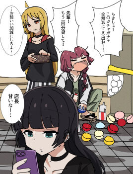 3girls ahoge aqua_eyes black_hair blonde_hair bocchi_the_rock! braid cellphone choker closed_eyes face_piercing gashapon geta goumonsha highres hiroi_kikuri ijichi_seika jacket labret_piercing letterman_jacket long_hair mouth_piercing multiple_girls orange_eyes pa-san phone piercing red_hair sharp_teeth smartphone squatting teeth translated wallet