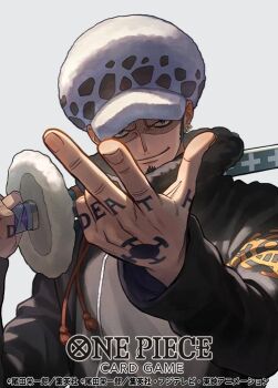 1boy black_coat closed_mouth coat commentary_request copyright_name earrings facial_hair goatee hand_tattoo hat holding holding_sword holding_weapon jewelry looking_at_viewer male_focus official_art one_piece one_piece_card_game otton sideburns simple_background smile solo sword tattoo trafalgar_law upper_body weapon