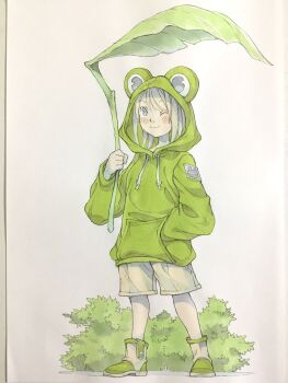 1girl animal_hood blonde_hair blue_eyes boots brown_pants bush closed_mouth commentary drawstring frog_hood full_body green_boots green_hoodie hand_in_pocket hand_up highres holding holding_leaf hood hood_up hoodie leaf leaf_umbrella looking_at_viewer one_eye_closed original pants peter_salt short_hair smile solo standing traditional_media