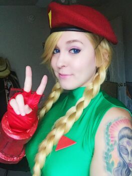 Rule 34 | 1girl, beret, blonde hair, blue eyes, blurry, blurry background, braid, cammy white, cammy white (cosplay), capcom, chelhellbunny, cosplay, female focus, gloves, hat, highres, indoors, leotard, looking at viewer, photo (medium), real life, red gloves, red hat, smile, solo, street fighter, v