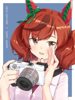 1girl alternate_costume animal_ears balladeluce blue_background border bow brown_eyes camera character_name commentary_request ear_bow ear_covers green_bow highres holding holding_camera horse_ears horse_girl jacket medium_hair multicolored_hair nail_polish nice_nature_(casual)_(umamusume) nice_nature_(umamusume) partially_unzipped purple_shirt red_hair red_nails shirt simple_background solo sony sony_α6000 streaked_hair twintails umamusume upper_body white_border white_jacket