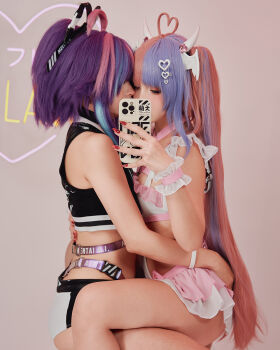 2girls cosplay fake_horns fingernails hair_ornament hairband heart heart_hair_ornament horns indie_virtual_youtuber ironmouse long_fingernails melody_(projektmelody) moeflavor_(company) multicolored_hair multiple_girls phone ponytail real_life red_nails selfie sitting sitting_on_lap sitting_on_person strap swimsuit swimsuit_skirt twintails two-tone_hair virtual_youtuber yuri