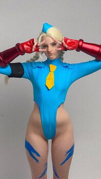 Rule 34 | 1girl, :<, bare legs, blonde hair, blue eyes, blue leotard, bodypaint, bow, bowtie, braid, brazilian (nationality), breasts, cammy white, cammy white (cosplay), cosplay, curvy, freckles, garrison cap, hat, highleg, highleg leotard, highres, indoors, leotard, long hair, memepantazis, parted lips, photo (medium), real life, simple background, sitting, smile, street fighter, street fighter alpha, thong leotard, twin braids, twitter username, v, wide hips