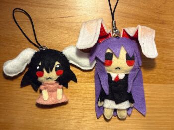 2girls :3 animal_ears aoiseshin arms_at_sides black_coat black_hair character_doll charm_(object) chibi closed_mouth coat commentary cropped_legs doll dress english_commentary felt_(medium) frown full_body hair_between_eyes highres inaba_tewi long_hair long_sidelocks looking_at_viewer lying medium_hair multiple_girls necktie on_back on_table photo_(medium) pink_dress purple_hair rabbit_ears red_eyes red_necktie reisen_udongein_inaba shirt sidelocks solo straight-on table touhou unconventional_media very_long_hair white_shirt wooden_table