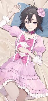 1girl absurdres antenna_hair bed_sheet black_hair closed_mouth dress flower frilled_dress frills grey_eyes hair_flower hair_ornament highres idolmaster idolmaster_(classic) juliet_sleeves kikuchi_makoto light_smile long_sleeves looking_at_viewer lying on_back on_bed pink_dress pink_flower puffy_sleeves short_hair solo yaki_tai