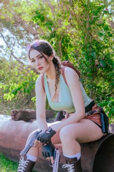 1girl argentine_(nationality) bare_arms black_gloves braid braided_ponytail breasts cleavage cosplay day fingerless_gloves gloves gun handgun highres holding holding_gun holding_weapon lara_croft lara_croft_(cosplay) lips looking_at_viewer medium_breasts real_life shirt short_shorts shorts single_braid sitting sophie_valentine sunglasses_on_head sunlight tomb_raider tree weapon wide_hips