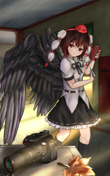 1girl bird_wings black_ribbon black_socks black_wings brown_eyes brown_hair buttons camera commentary door feathered_wings frilled_skirt frills galm_x_lmr_(ryonasa) garage hat highres holding holding_pen indoors leaf_fan light_rays looking_at_object neck_ribbon object_request open_mouth parted_lips pen pom_pom_(clothes) puffy_short_sleeves puffy_sleeves red_hat ribbon ribbon-trimmed_skirt ribbon_trim shameimaru_aya short_hair short_sleeves skirt sleeve_cuffs socks solo table tokin_hat touhou variant_set_available wings