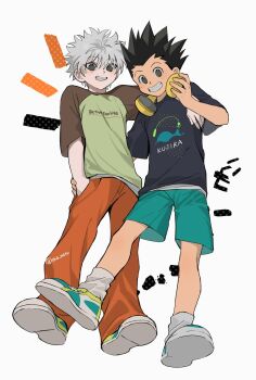 2boys alternate_costume black_hair black_shirt blue_eyes brown_eyes commentary crew_neck full_body gon_freecss green_shorts grin headphones headphones_around_neck highres hunter_x_hunter killua_zoldyck male_focus multiple_boys pants print_shirt red_pants sha_nato shirt shoes short_hair short_sleeves shorts simple_background smile socks spiked_hair standing symbol-only_commentary t-shirt teeth twitter_username white_background white_hair white_socks widow's_peak