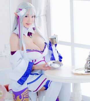 1girl breasts cosplay cup emilia_(re:zero) emilia_(re:zero)_(cosplay) female_focus grey_hair highres holding holding_cup large_breasts long_hair looking_at_viewer model photo_(medium) pointy_ears purple_eyes re:zero_kara_hajimeru_isekai_seikatsu shibuya_kaho sitting smile solo