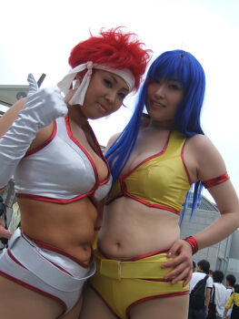 2girls belt blue_eyes breasts cleavage cosplay_photo crop_top dark_skin dirty_pair dutch_angle hand_on_own_hip headband kei_(dirty_pair) kei_(dirty_pair)_(cosplay) long_hair multiple_girls navel outdoors photo_(medium) plump real_life red_hair short_hair short_shorts shorts yuri_(dirty_pair) yuri_(dirty_pair)_(cosplay)