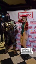 1girl 2boys animated argentine_(nationality) armor bare_shoulders blonde_hair braid breasts cammy_white cammy_white_(cosplay) cape cosplay din_djarin din_djarin_(cosplay) fighting_stance fingerless_gloves from_behind gloves grogu hat highleg highleg_leotard highres holding holding_weapon instagram_username leotard long_hair mandalorian mandalorian_helmet multiple_boys multiple_views parted_lips photo_(medium) real_life skindentation sleeveless smile sophie_valentine sound star_wars street_fighter the_mandalorian thong_leotard twin_braids very_long_hair video weapon