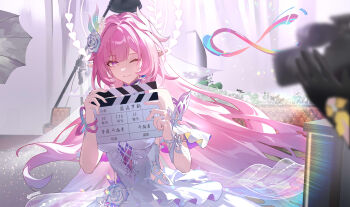 2girls ;) absurdres amphoreus_(honkai:_star_rail) animal_ears black_gloves breasts bridal_veil chinese_commentary clapperboard commentary_request cyrene_(honkai:_star_rail) cyrene_(ripples_of_past_reverie)_(honkai:_star_rail) diamond-shaped_pupils diamond_(shape) dress gloves halo highres holding honkai:_star_rail honkai_(series) indoors large_breasts long_hair looking_at_viewer mobius_strip movie_camera multiple_girls mumu123 one_eye_closed pink_hair pointy_ears purple_eyes smile stelle_(honkai:_star_rail) symbol-shaped_pupils trailblazer_(honkai:_star_rail) veil very_long_hair white_dress