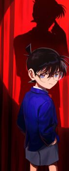 1boy :/ black_hair blue_eyes blue_jacket closed_mouth cowboy_shot curtains different_shadow edogawa_conan glasses grey_shorts hands_in_pockets highres jacket kudou_shin'ichi looking_at_viewer looking_back male_focus meitantei_conan segami short_hair shorts solo spotlight stage_curtains