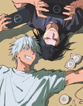 2boys 9999_kka absurdres arms_up black_hair black_shirt blue_eyes commentary crew_neck english_commentary from_above getou_suguru gojou_satoru grin handheld_game_console highres holding holding_handheld_game_console jujutsu_kaisen looking_at_another looking_at_object looking_to_the_side lying male_focus multiple_boys on_back parted_hair playstation_portable shirt short_sleeves smile teeth upper_body white_hair white_shirt