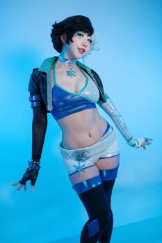 1girl 2025 absurdres arms_at_sides asian asymmetrical_gloves belt black_boots black_gloves black_hair black_jacket blue_background blue_eyes blue_eyeshadow blue_nails boots border breasts choker cleavage collarbone contrapposto cosplay cosplay_photo cowboy_shot crop_top cropped_jacket danisaurz earrings eyeshadow female_focus fingerless_gloves fingernails full_body gloves grin hair_between_eyes heterochromia highres indoors jacket jewelry large_breasts long_fingernails looking_at_viewer luna_snow luna_snow_(cosplay) marvel marvel_rivals midriff mismatched_gloves multicolored_hair multiple_rings navel open_clothes open_jacket parted_hair partially_fingerless_gloves photo_(medium) purple_eyes real_life red_lips ring short_hair short_shorts shorts sidelocks simple_background skindentation smile solo split-color_hair thick_lips thigh_boots two-tone_hair wedge_heels white_belt white_border white_choker white_eyeshadow white_gloves white_hair white_nails white_shorts